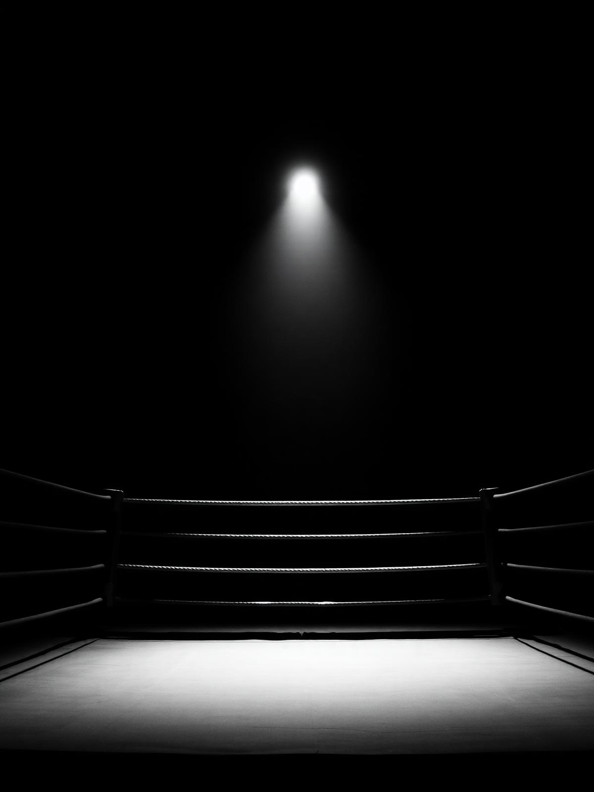 Empty boxing ring under a single spotlight